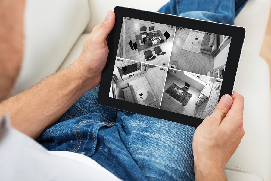 Man Sitting On Sofa While Monitoring Video Footage on a Tablet